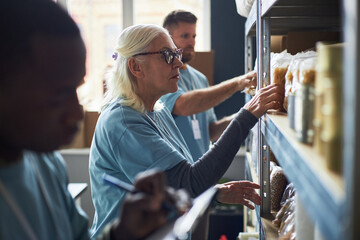 Team of workers organizing items on shelves in storage area at workplace, focusing on tasks....