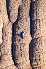 Top down aerial of a man laying on white sandstone rocks at White Pocket in Vermillion Cliffs of Northern Arizona.  Photographed with a drone at sunset.