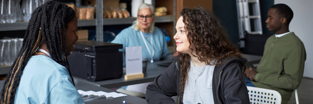Diverse group of volunteers engaging in conversation and collaborative activities in community center highlighting teamwork and mutual support