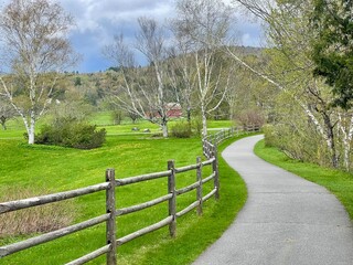 Walking bike path winds through the green countryside, farms, and mountains of Vermont in this picturesque scene