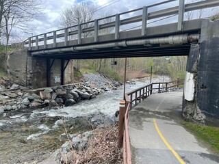 A walking bridge crosses a river in the Vermont countryside