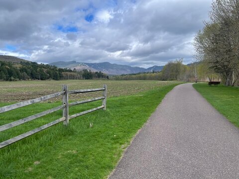 Walking bike path winds through the green countryside, farms, and mountains of Vermont in this picturesque scene