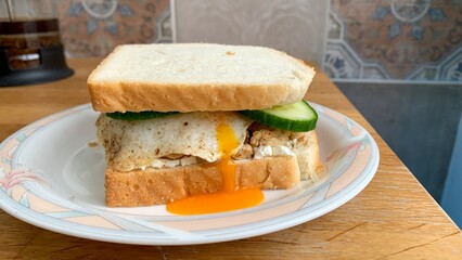 A golden yolk oozing from a rustic egg sandwich, evoking cozy brunch vibes, perfect for National...