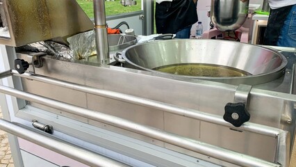 A bustling street fair's metal syrup cauldron bubbles with golden sweetness, evoking Pancake Day...