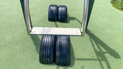 Rubber tires rest serenely on a playground's pale jade surface, echoing Earth Day's renewable...
