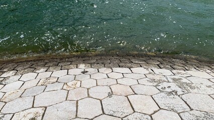 Hexagonal pathway kisses mossy tides, evoking tranquility, lunar New Year reflections, tranquil...