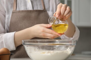 Making khinkali. Woman adding oil into bowl at table in kitchen, closeup