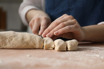 Making khinkali. Woman portioning dough at table in kitchen, closeup
