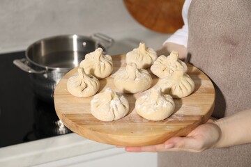 Woman with many uncooked khinkali in kitchen, closeup