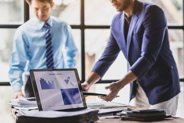 Two businessman discussing financial charts on laptop in office. Analyzing data. Strategizing. And planning for success. Teamwork and collaboration towards growth and success in business.