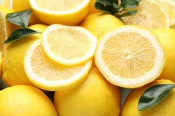 Fresh ripe lemons and leaves as background, closeup