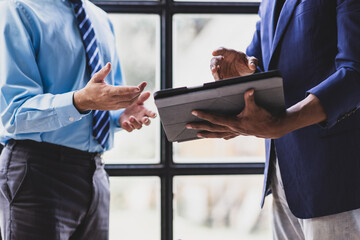 Two young businessman are discussing work, showing something on
