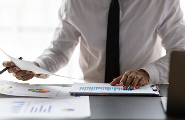 Businessman analyzing charts and graphs in the office. He is working on accounting and financial...