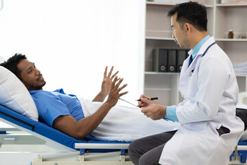 Obraz premium Doctor attending patient lying in hospital bed. Doctor visits patient in hospital room.