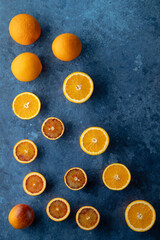 Fresh oranges and blood oranges creating a colorful pattern on a blue background