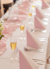 Elegant table setting with champagne glasses and pink napkins is waiting for wedding guests