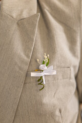 Groom wearing light gray suit with white rose boutonniere and white ribbon