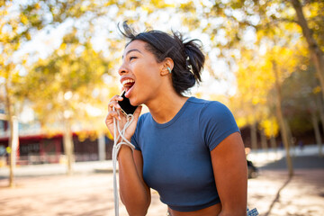 side portrait of a young woman enthusiastically talking on the phone outdoors