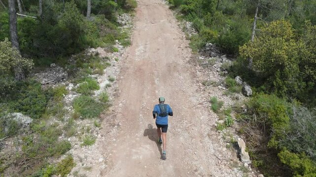 Male athlete running along a dirt path in a serene pine forest, embracing the peacefulness of nature while engaging in a vigorous workout and enhancing his fitness journey