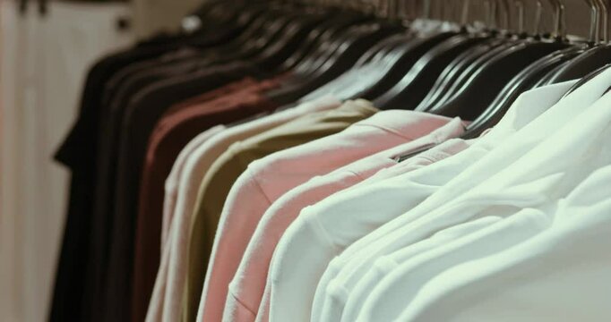 Vibrant t shirts suspended on minimalist black hangers showcasing diverse sizes and colors, presenting stylish clothing selection within retail merchandising environment