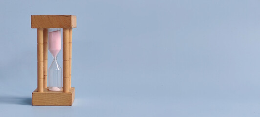 Sand Clock on Blue Background Representing Time, Patience, and the Passage of Moments