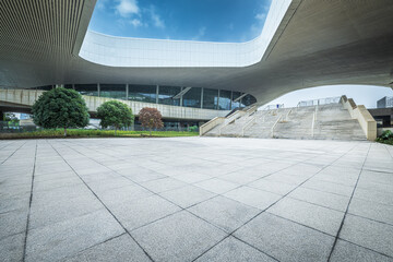 Wide empty brick floor extending beneath modern public building.
