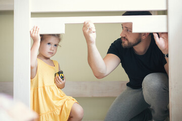 Young man with his daughter assembling furniture at home