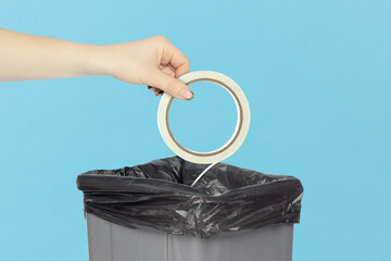 throwing double sided adhesive tape into trash, outstretched hand with roll of narrow double-sided...