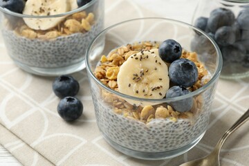 Delicious dessert with chia seeds, yogurt, granola, blueberries and banana on table, closeup. Superfood