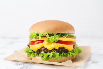 Tasty cheeseburger on white marble table, closeup