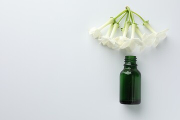 Bottle of essential oil and jasmine flowers on white background, flat lay. Space for text