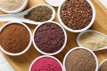 Different superfoods in bowls and spoons on table, top view