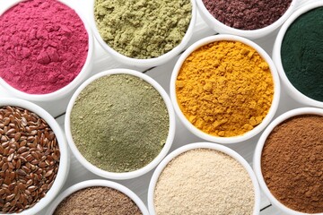 Different superfood powders in bowls on white wooden table, flat lay