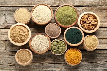 Different superfoods in bowls on wooden table, flat lay