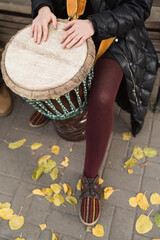 European woman playing an African drum djembe outdoors in autumn