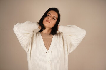 A woman in a cozy white sweater has her eyes gently closed
