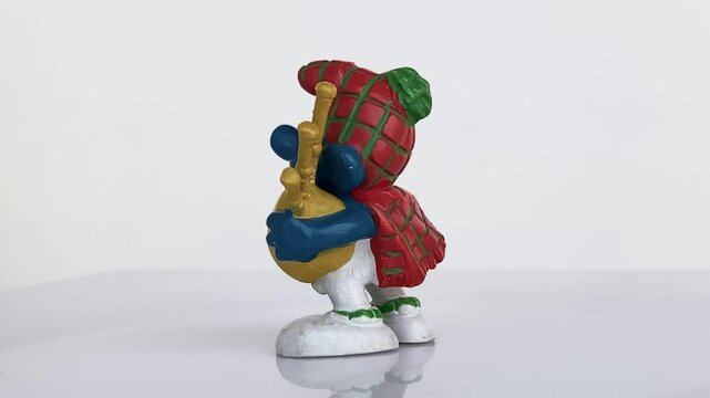 Figura original de pitufo con gaita. Juguete rotando. Fondo blanco