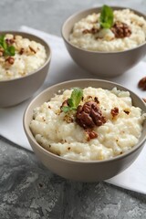 Delicious rice pudding with walnuts and mint on grey table, closeup