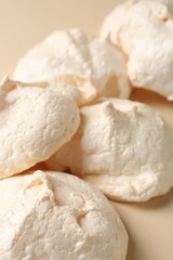 Delicious homemade meringue cookies on beige background, closeup