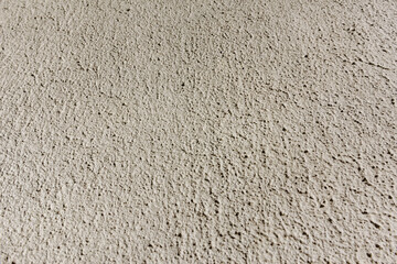 Close-up, background texture of a beige facade wall of a house made of decorative plaster. Abstract surface.