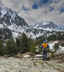 Hiker contemplating snowy mountain peaks in the pyrenees during spring.