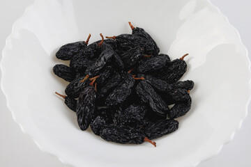 Black raisins in a white plate.