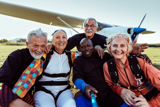 Group of senior people taking a selfie after skydiving on a field