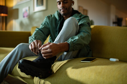 Middle aged african american man tying his shoelaces and getting ready to go jogging and exercising at home