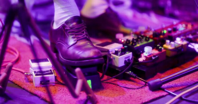 a close up of a shoe pressing guitar pedals at a concert