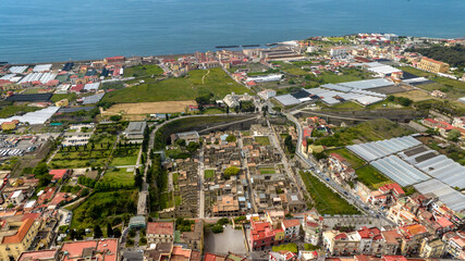 Aerial view of the archaeological area of ​​the excavations of Herculaneum located in the province of Naples, Campania, Italy. It is an archaeological area. In the background is the Mediterranean sea.