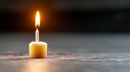 Burning Candle on a Small Cake Isolated with a Dark Background