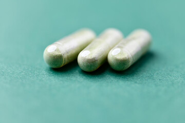 Barley grass capsules. Antioxidants. Concept for a healthy dietary supplementation. Bright background. Soft focus. Close up. Copy space.	
