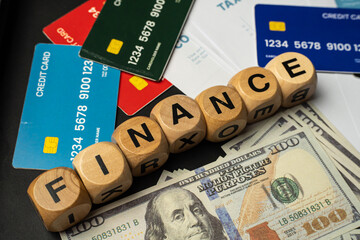 Business and finance background image showing a blend of paper currency, credit cards, profit charts, and tax files. The word “FINANCE” arranged with wooden letter blocks adds a creative touch