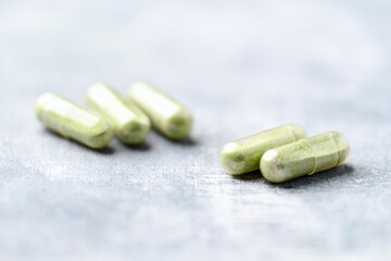 Barley grass capsules. Antioxidants. Concept for a healthy dietary supplementation. Bright background. Soft focus. Close up. Copy space.